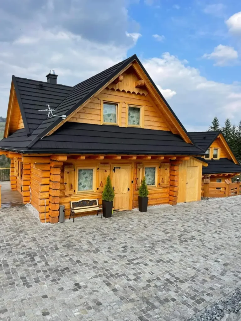 dwa domki z bali, okna, drzwi, kostka brukowa przed domkami